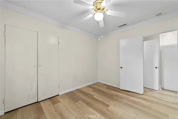 an empty room with wooden floor fan and windows