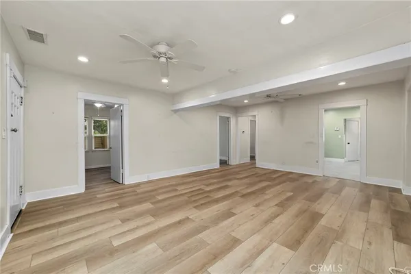 a view of an empty room with window and wooden floor