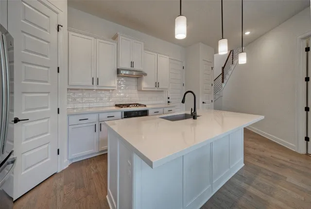 a kitchen with stainless steel appliances granite countertop a sink a stove and a refrigerator