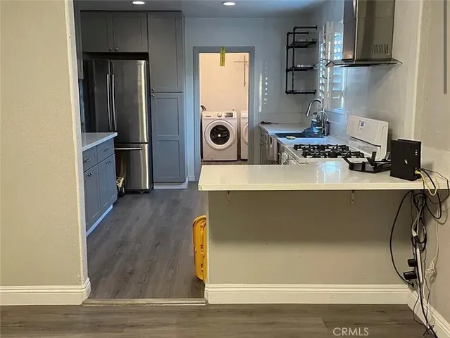 a living room with kitchen island a wooden floor and refrigerator