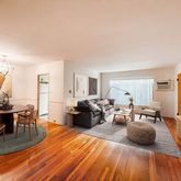 a living room with furniture a large window and wooden floor