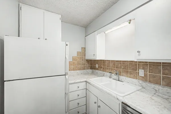 a kitchen with a sink a refrigerator and cabinets