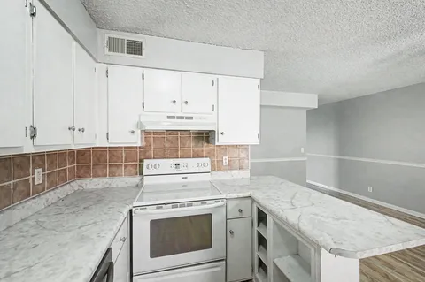 a kitchen with granite countertop white cabinets and white appliances
