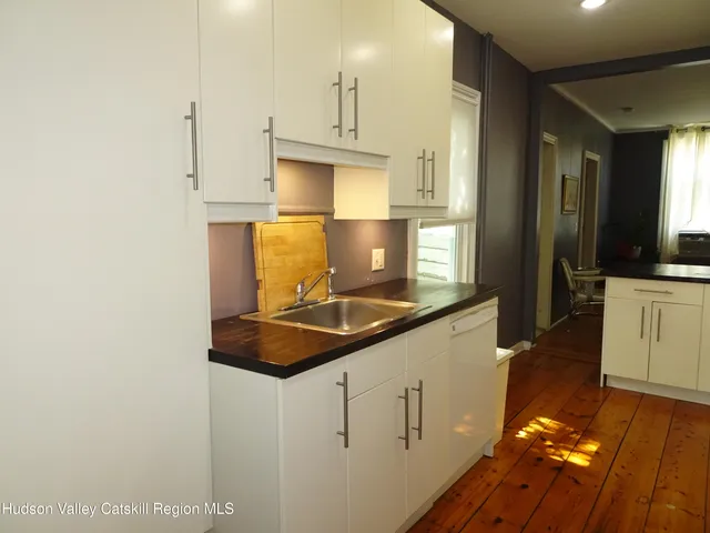 a kitchen with stainless steel appliances granite countertop a sink a stove and white cabinets with wooden floor