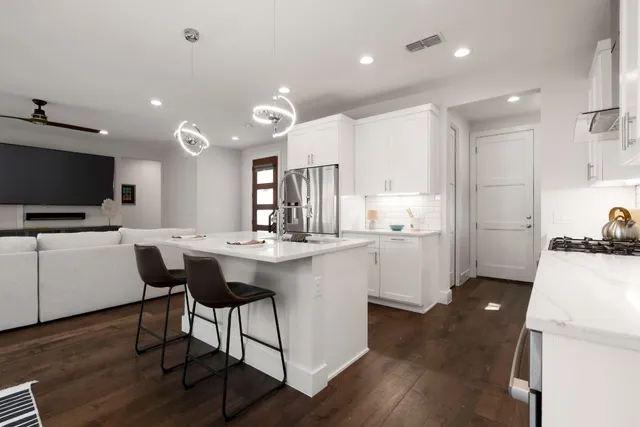 a kitchen with stainless steel appliances kitchen island granite countertop a stove a sink a dining table and chairs