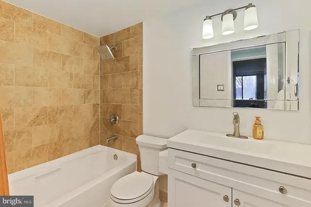 a bathroom with a toilet a sink a mirror and bathtub