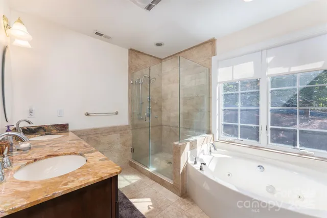 a bathroom with a granite countertop tub sink and mirror