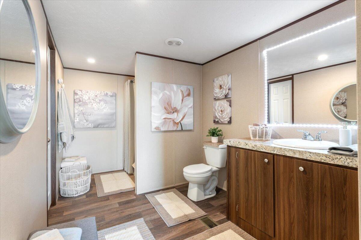 508 Sage Road Tahoka, TX 79373 - Photo 12 of 26 a bathroom with a granite countertop toilet a sink a mirror and a glass door