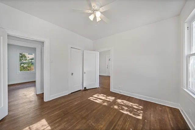 a view of empty room with wooden floor and fan