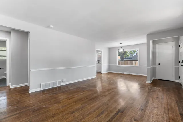 an empty room with wooden floor and window
