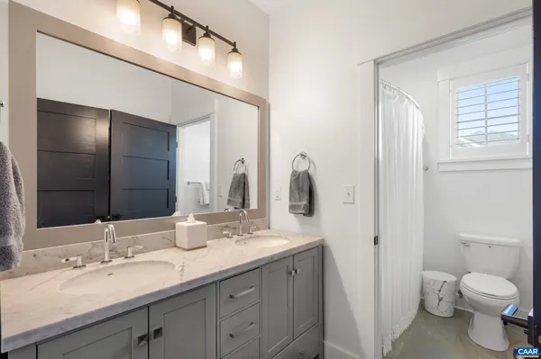 a bathroom with a double vanity sink toilet and a mirror