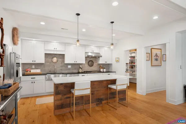 a kitchen with stainless steel appliances kitchen island granite countertop a table chairs sink and cabinets