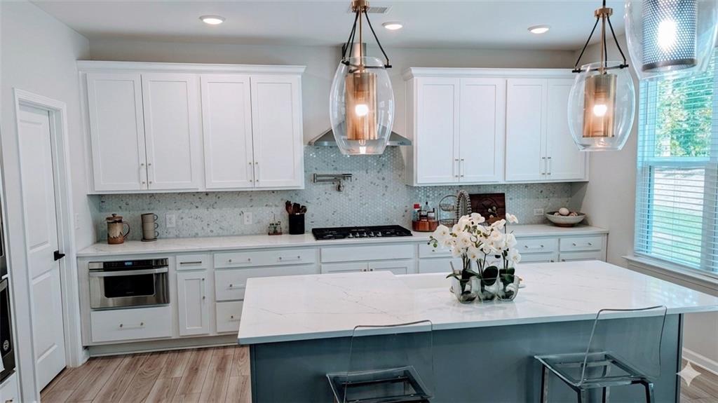 4830 Spangle Court Cumming, GA 30028 - Photo 4 of 18 a kitchen with kitchen island granite countertop a stove a white cabinets a sink and white cabinets