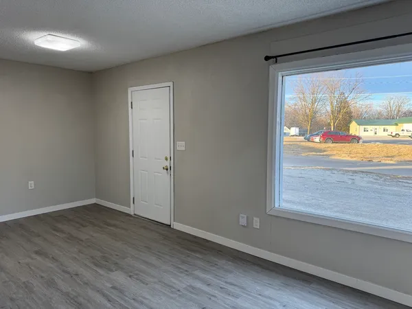 an empty room with wooden floor and windows