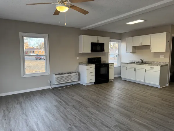 a view of kitchen with stainless steel appliances granite countertop a stove top oven a sink with wooden floors and cabinets