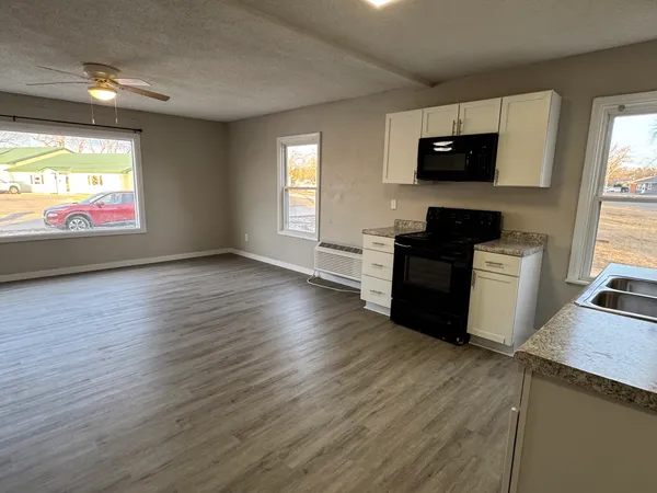 a view of a kitchen with wooden floor electronic appliances and furniture