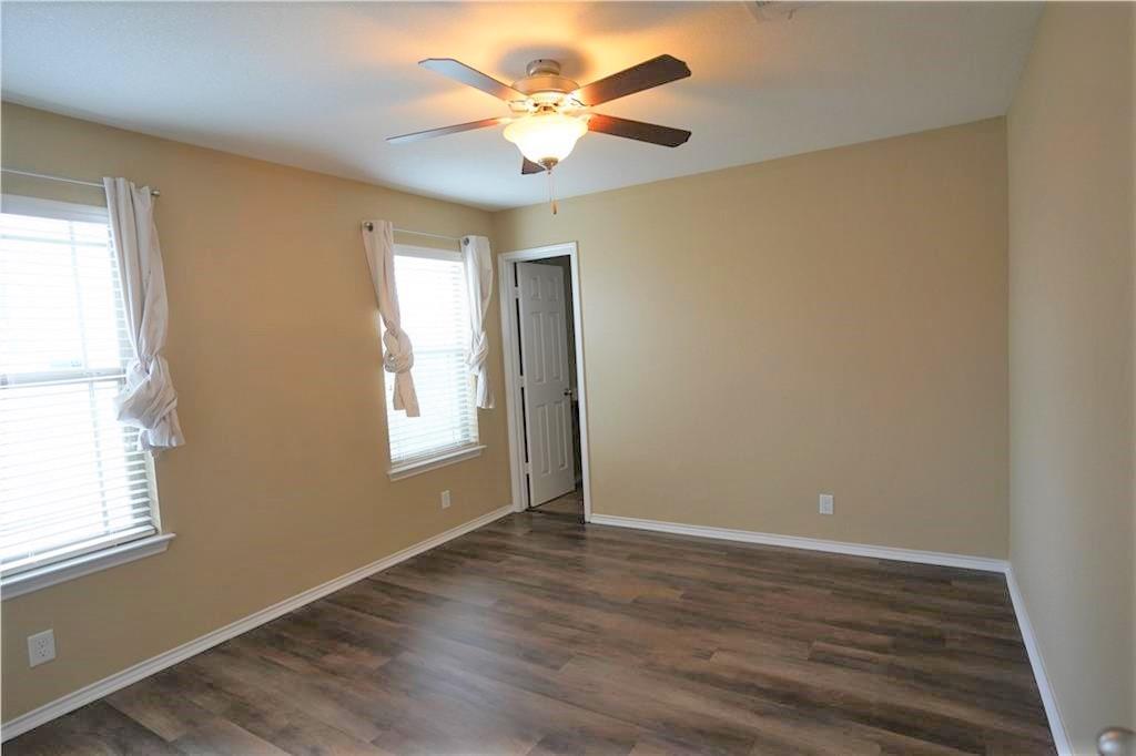 201 Edwin Kyle, TX 78640 - Photo 10 of 21 Spacious room featuring wood-finish flooring, two windows with blinds, a ceiling fan with integrated lighting, and neutral wall tones