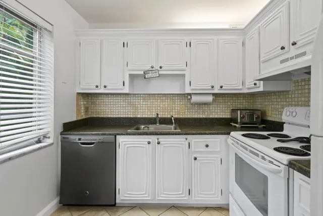 a kitchen with granite countertop white cabinets and stainless steel appliances