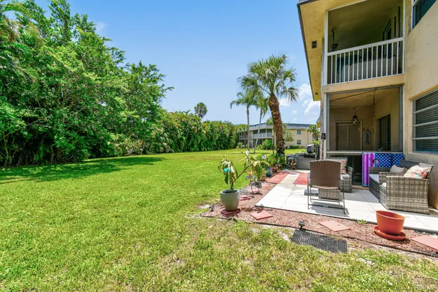 a view of a patio with a table chairs and a small yard