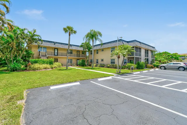 a view of a white house with a big yard and potted plants