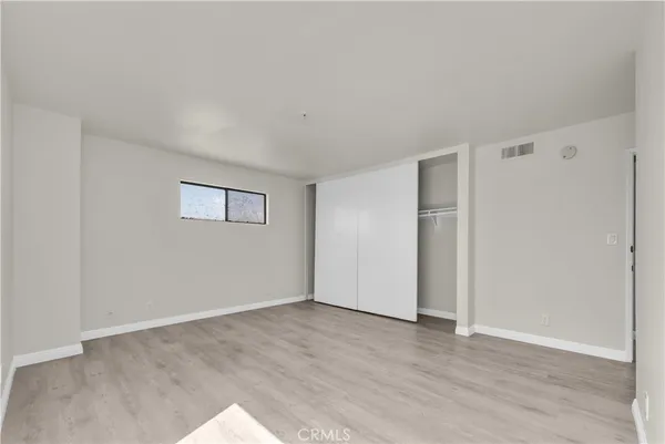 a view of an empty room with wooden floor and closet