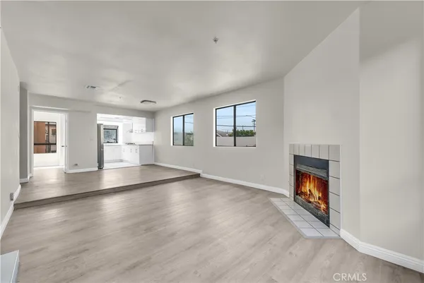 an empty room with wooden floor fireplace and windows