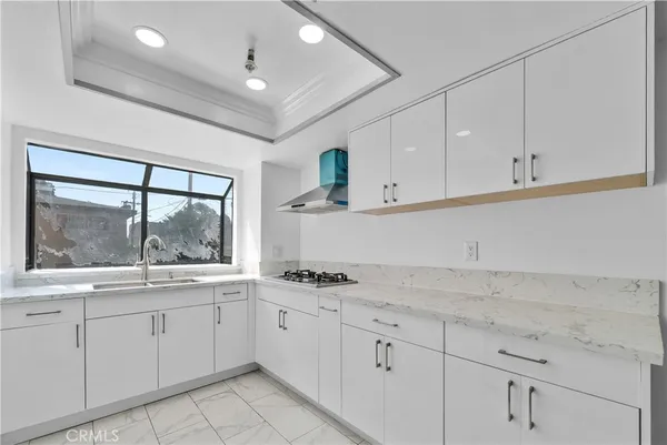 a kitchen with white cabinets and window