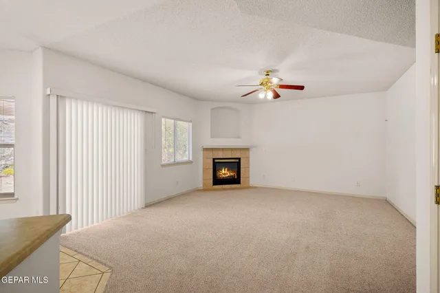 an empty room with a ceiling fan and a fireplace