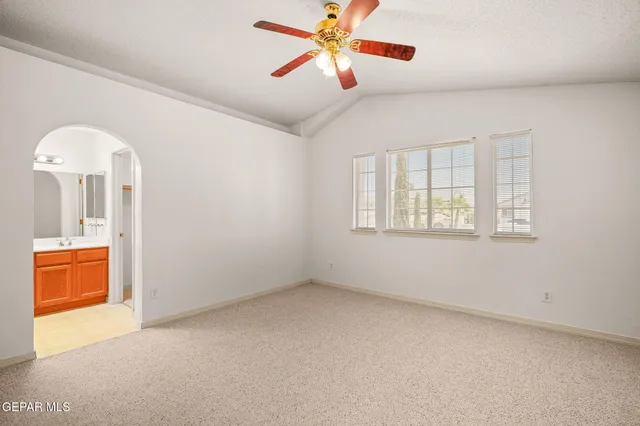 an empty room with chandelier fan and windows