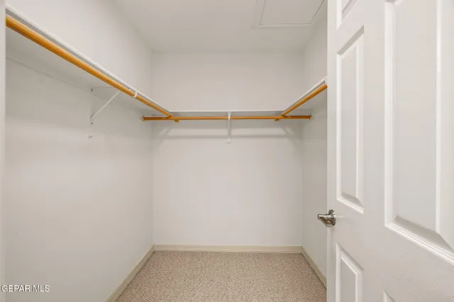 an empty room with chandelier fan and windows