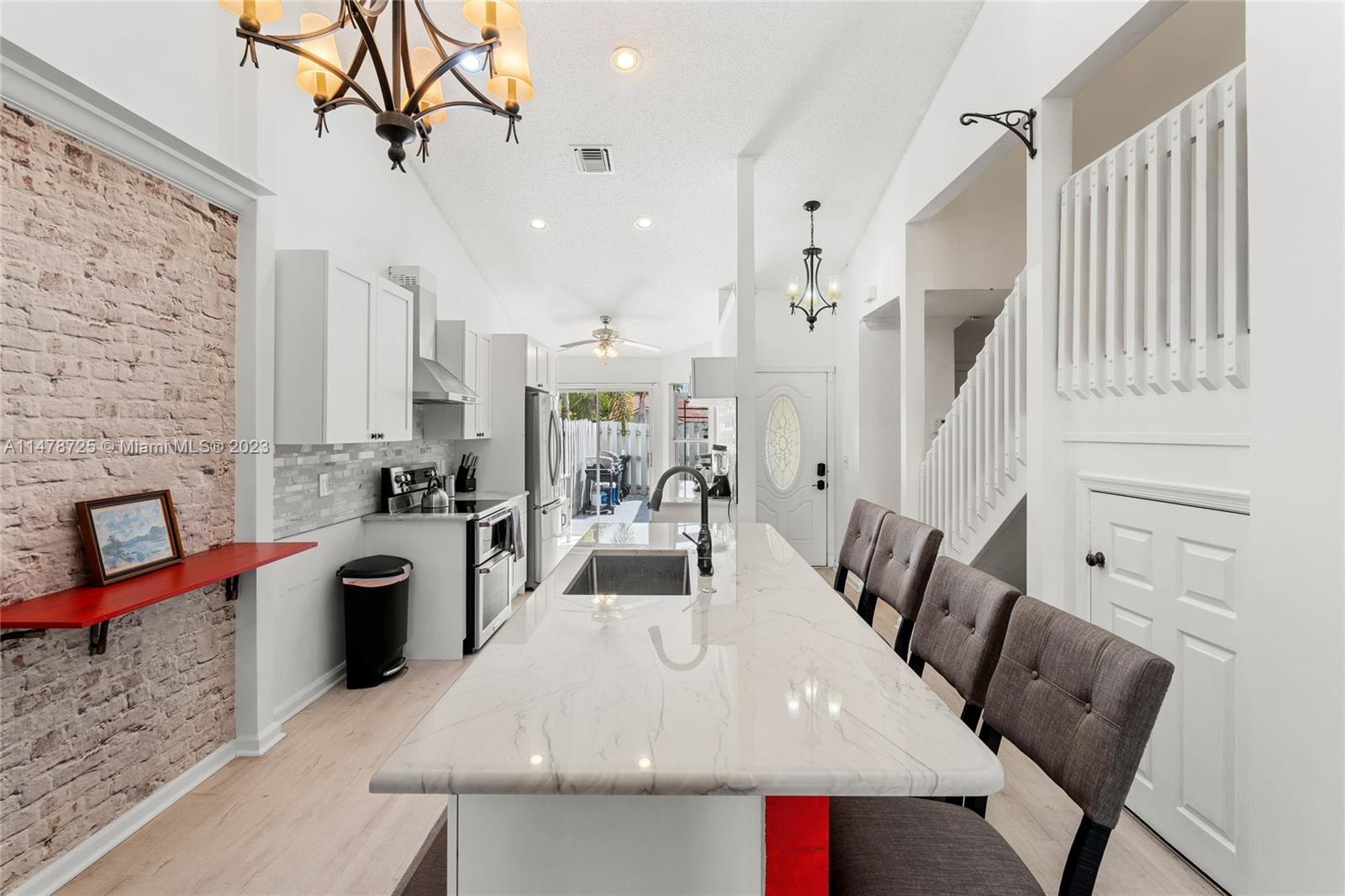 12722 Westhampton Circle Wellington, FL 33414 - Photo 19 of 52 a large kitchen with stainless steel appliances kitchen island granite countertop a table chairs in it and a wooden floor