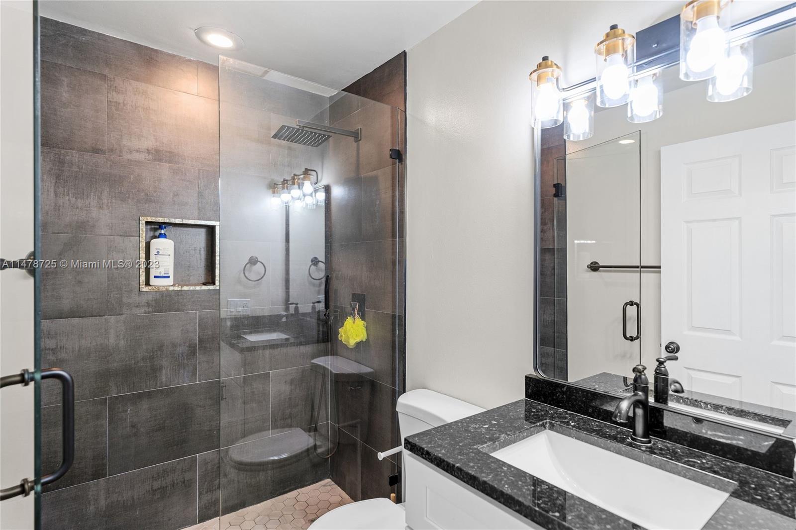 12722 Westhampton Circle Wellington, FL 33414 - Photo 24 of 52 a bathroom with a granite countertop sink a mirror and shower