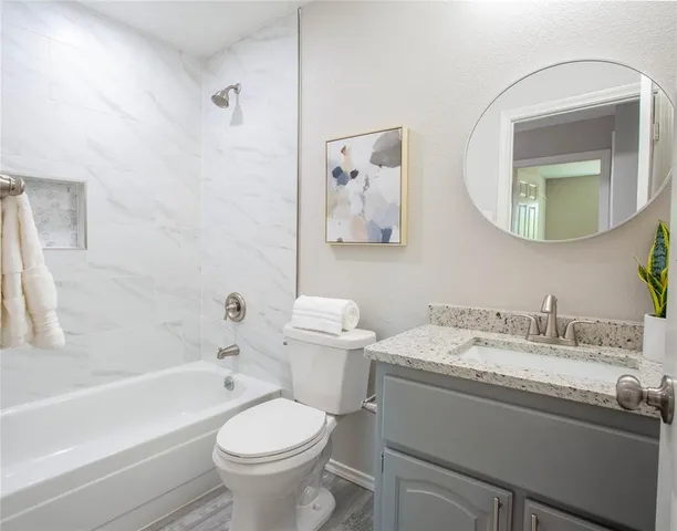 a bathroom with a granite countertop toilet a sink and a mirror