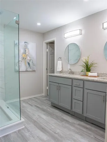 a spacious bathroom with a granite countertop sink a mirror and shower