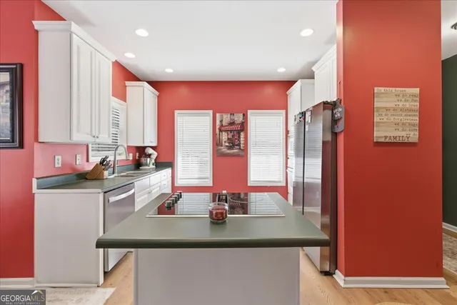 a kitchen with stainless steel appliances kitchen island granite countertop a sink and a refrigerator