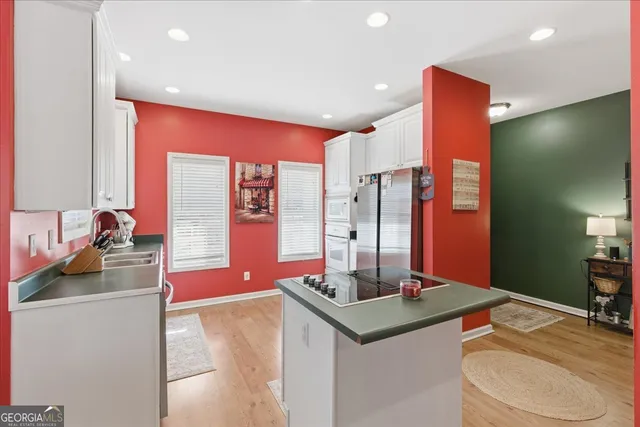 a large kitchen with kitchen island granite countertop a large window and white cabinets