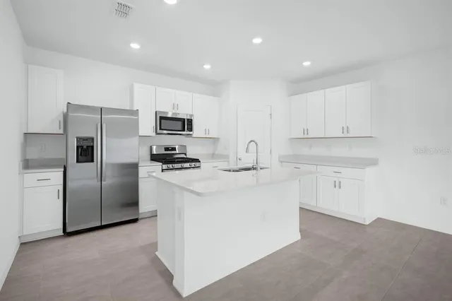 a view of kitchen with kitchen island and stainless steel appliances