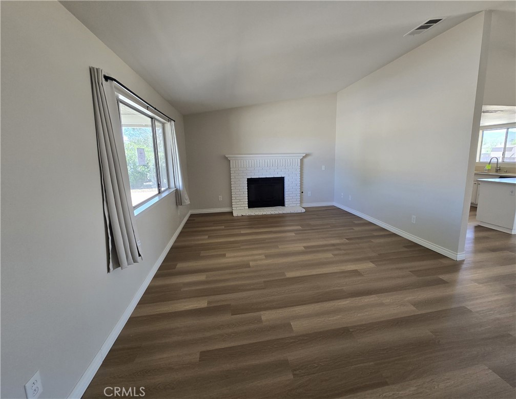 22909 Eyota Road Apple Valley, CA 92308 - Photo 2 of 18 a view of a livingroom with wooden floor and a fireplace