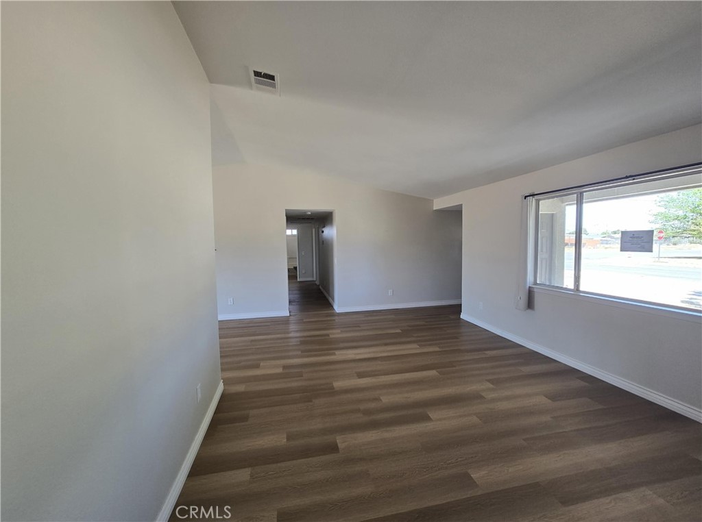 22909 Eyota Road Apple Valley, CA 92308 - Photo 3 of 18 a view of an empty room with wooden floor and a window
