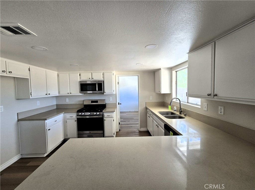 22909 Eyota Road Apple Valley, CA 92308 - Photo 6 of 18 a kitchen with stainless steel appliances granite countertop a sink dishwasher stove and refrigerator