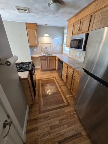 a view of kitchen and empty room with wooden floor