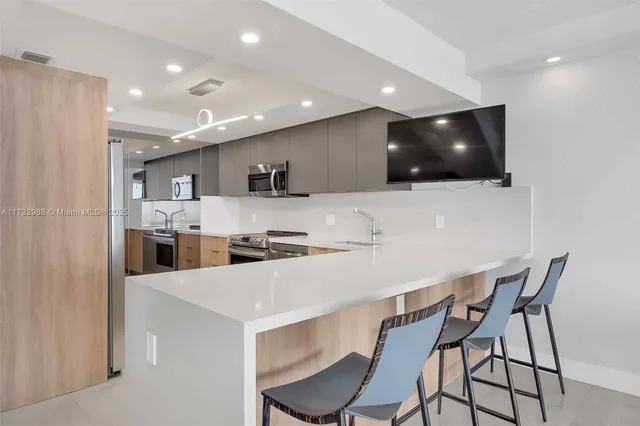 a kitchen with stainless steel appliances a white table chairs refrigerator and microwave