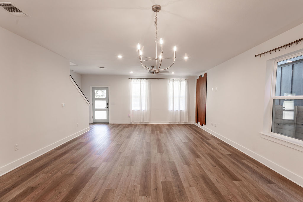Rich wood-inspired flooring pairs beautifully with the crisp walls and classic chandelier.