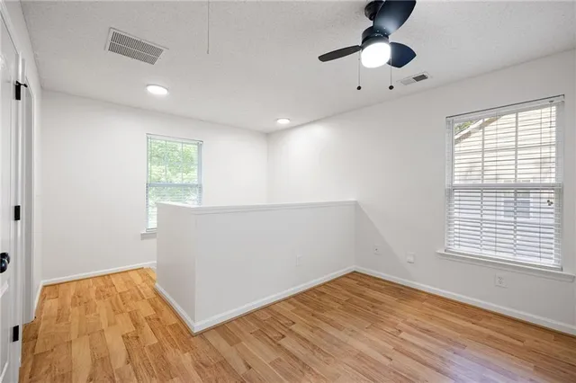 a view of empty room with wooden floor and fan