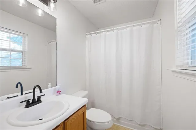 a view of a hallway to a room with wooden floor and cabinet