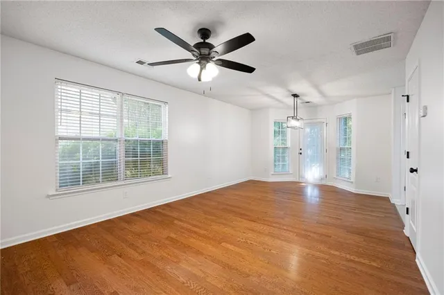 a view of an empty room with a window and a kitchen