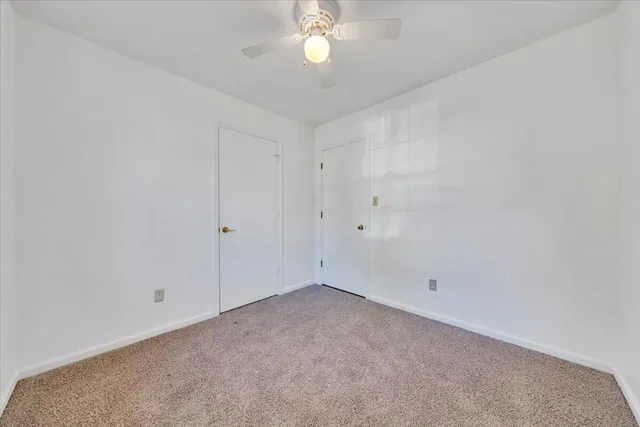 a view of an empty room with a chandelier fan