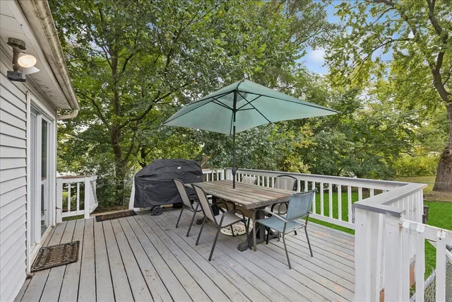a view of a roof deck with table and chairs under an umbrella with wooden floor and fence