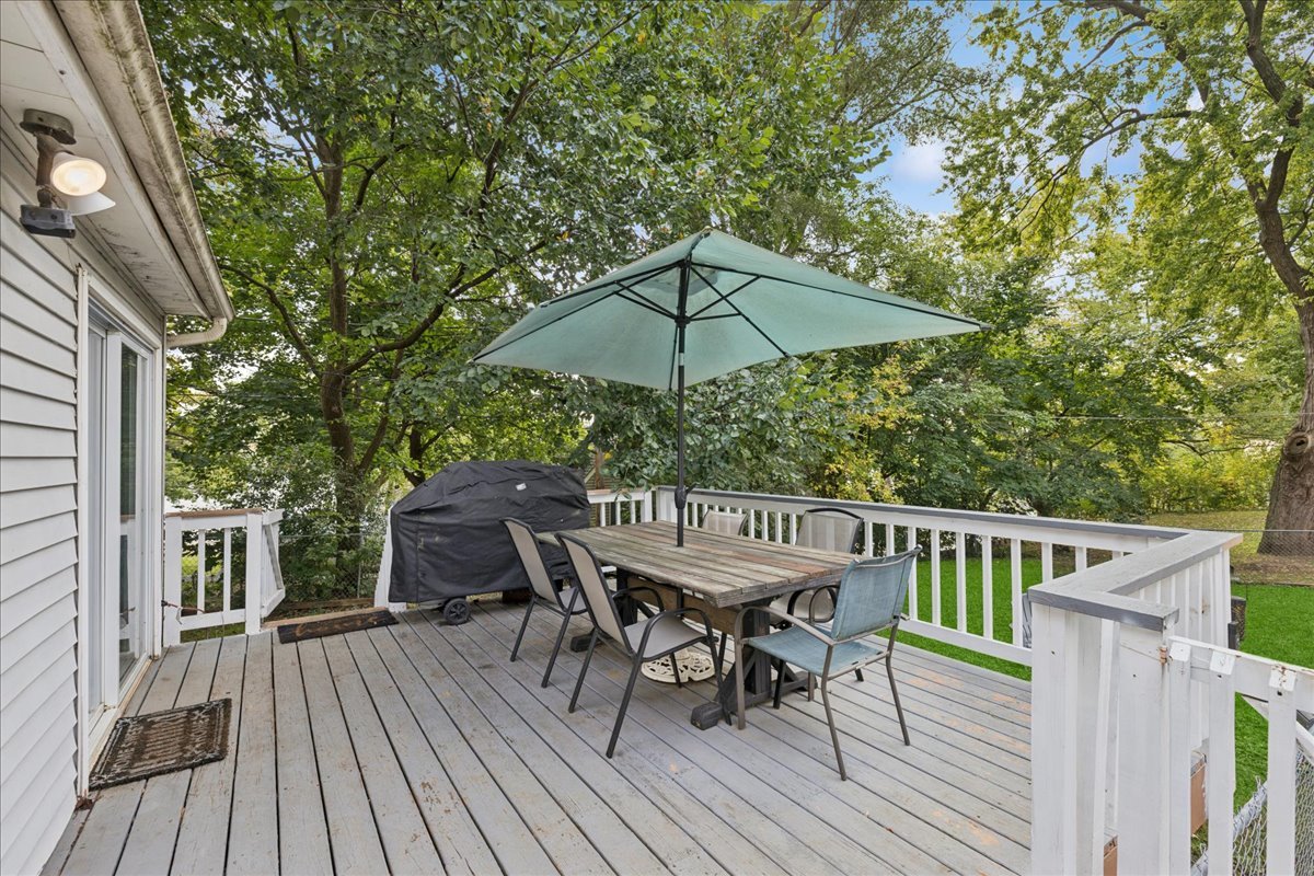 5116 Willow Drive Wonder Lake, IL 60097 - Photo 13 of 15 a view of a roof deck with table and chairs under an umbrella with wooden floor and fence