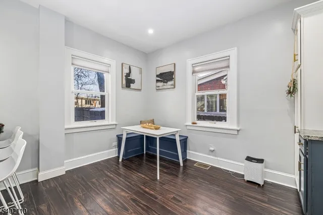 a kitchen with stainless steel appliances kitchen island granite countertop a stove a refrigerator a sink a dining table and chairs with wooden floor